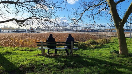 Mensen op bankje die naar het water en de haven kijken